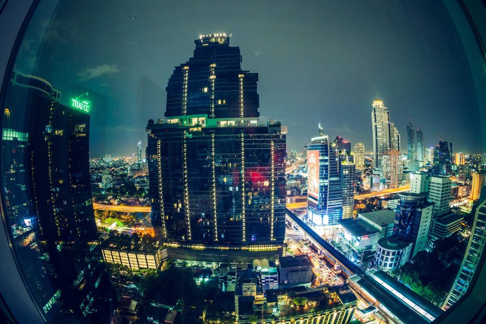 Night-time view of a city from a building through a curved window.