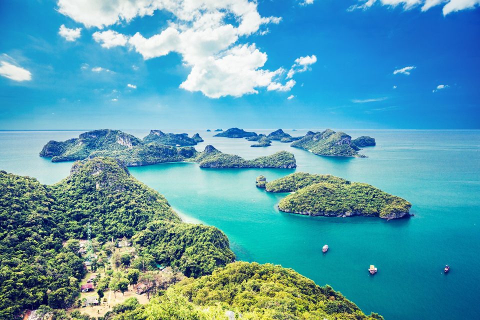 A panoramic view shows a tropical archipelago with numerous vegetation-covered islands surrounded by turquoise waters.