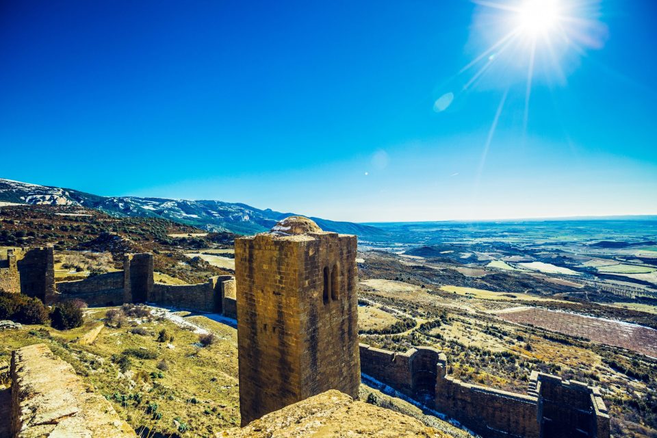 Panoramic view of a stone fortress with towers and walls over a mountainous landscape.