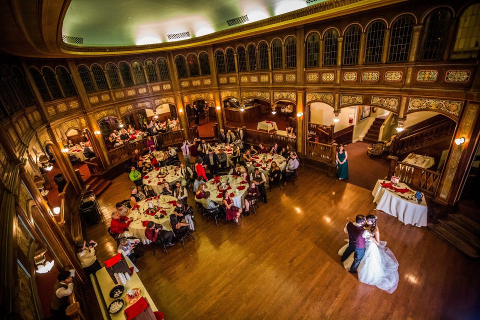 This is a panoramic view from an upper level of an ornate wood-panelled hall with tall windows.
